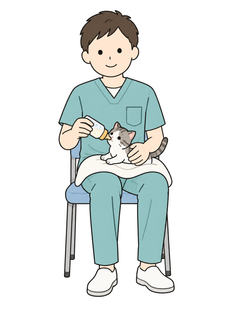 椅子に座った男性が膝のタオルの上で子猫を支え、小さな哺乳瓶でミルクを与えている。